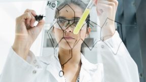 Une étudiante en médecine dessine des atomes sur une paroi en verre dans son laboratoire.