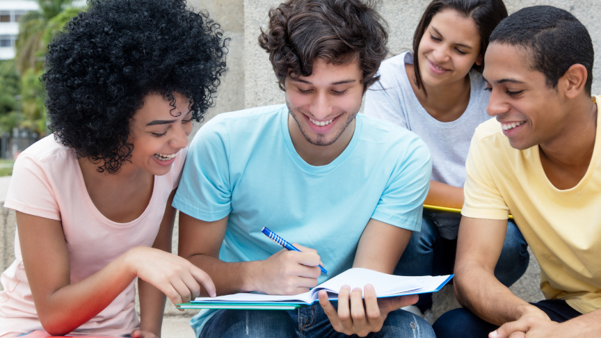 Un groupe d'étudiants multiethniques étudie en plein air sur le campus en été.